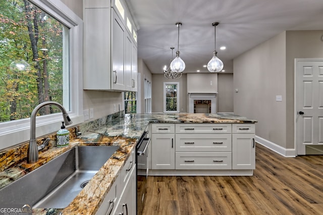 kitchen featuring dark wood-style floors, a sink, white cabinets, dishwasher, and decorative light fixtures