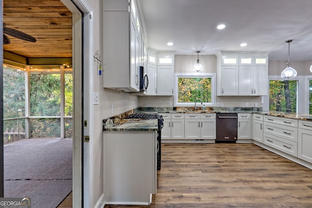 kitchen featuring stone countertops, stainless steel appliances, white cabinetry, glass insert cabinets, and pendant lighting