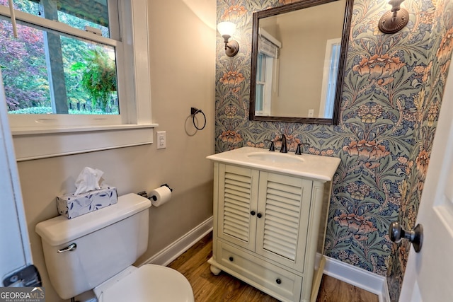 bathroom with toilet, baseboards, wood finished floors, and vanity