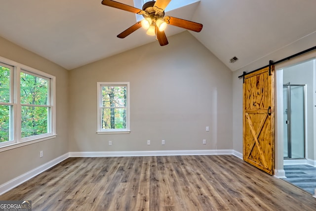 unfurnished room with a healthy amount of sunlight, a barn door, and wood finished floors