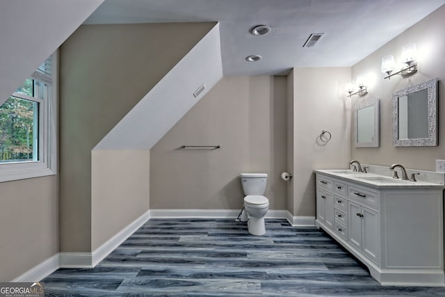 bathroom featuring visible vents, baseboards, toilet, wood finished floors, and a sink