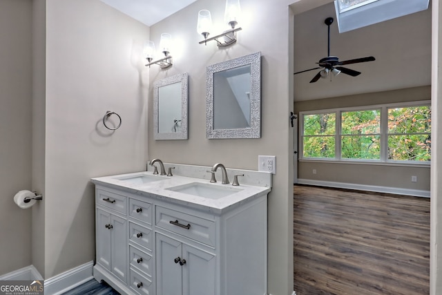 bathroom featuring a ceiling fan, a sink, baseboards, and double vanity