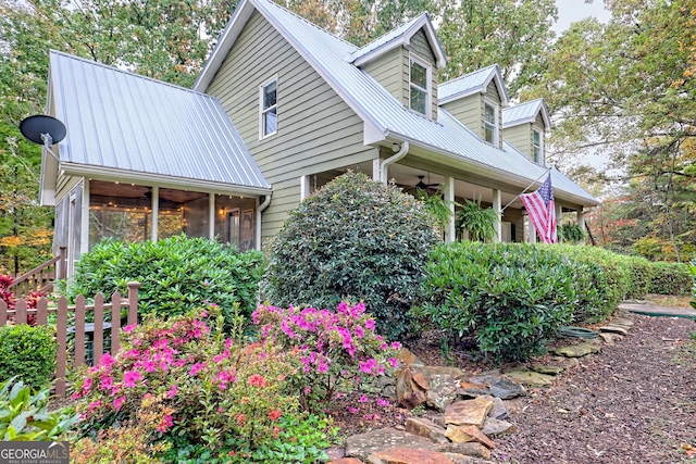 view of home's exterior featuring a sunroom, metal roof, and a ceiling fan