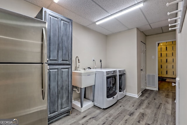 laundry room featuring light wood-style flooring, visible vents, cabinet space, and washer and clothes dryer