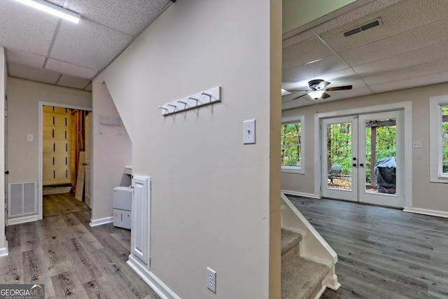 hall with light wood-style flooring, visible vents, and a drop ceiling