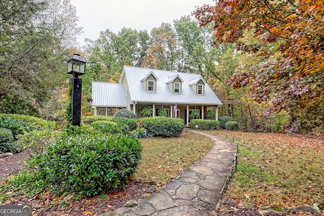 cape cod home with covered porch and metal roof