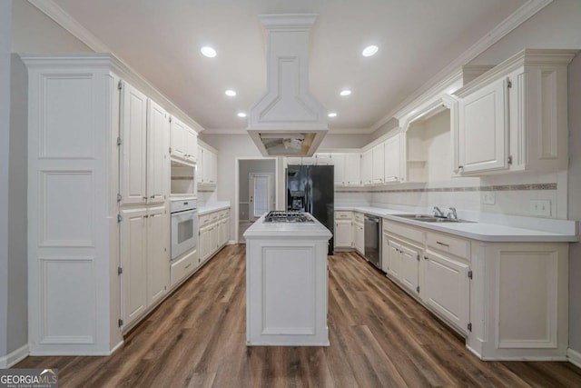 kitchen featuring appliances with stainless steel finishes, a center island, white cabinets, and light countertops