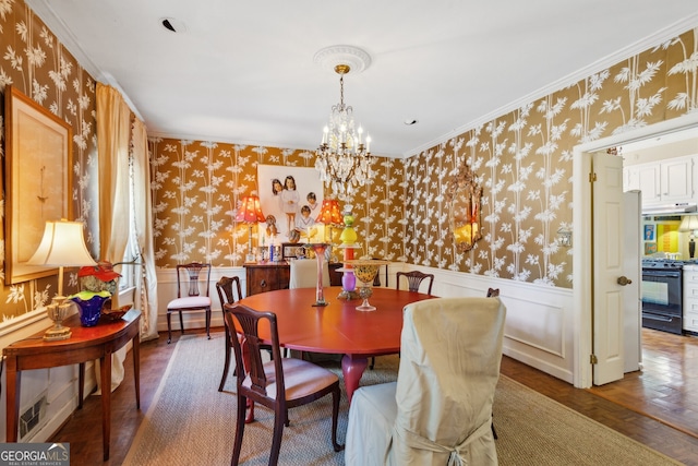 dining space featuring wallpapered walls, a wainscoted wall, and an inviting chandelier