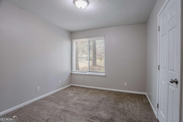 carpeted empty room featuring a textured ceiling and baseboards