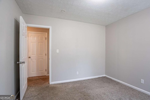 spare room featuring a textured ceiling, carpet flooring, and baseboards