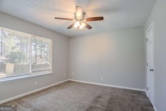 empty room featuring a textured ceiling, carpet floors, a ceiling fan, and baseboards