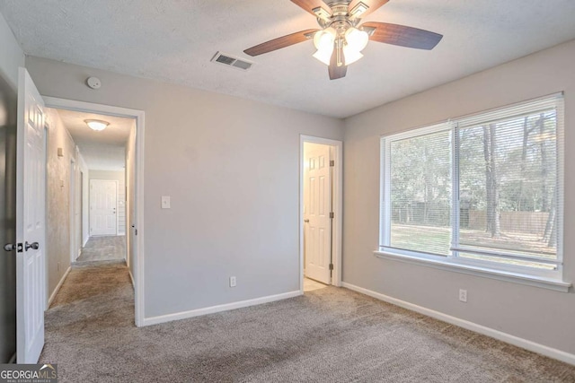 unfurnished bedroom featuring baseboards, visible vents, a textured ceiling, and light colored carpet