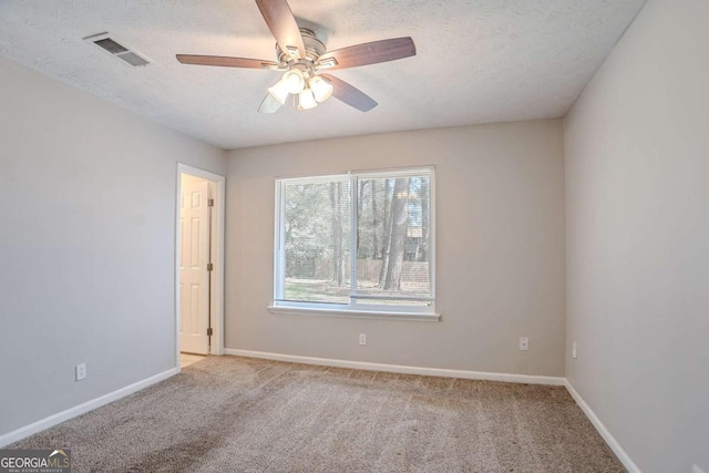 empty room featuring light carpet, visible vents, a textured ceiling, and baseboards