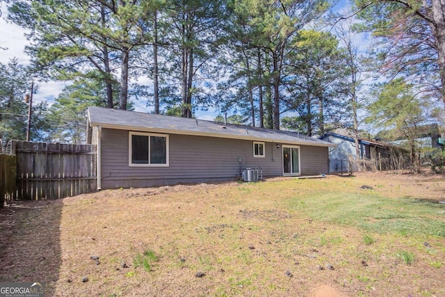 back of property with a yard, central AC unit, and fence