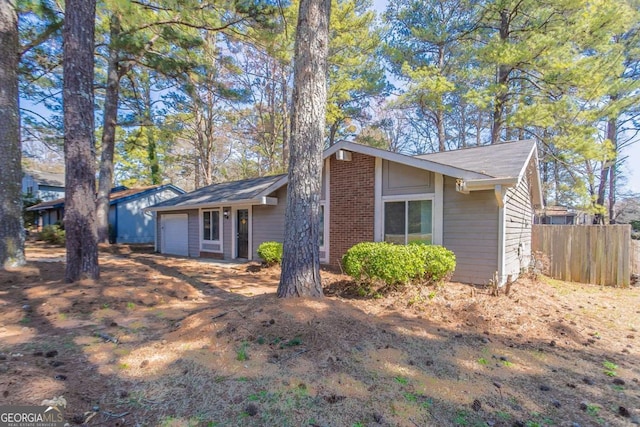 view of front of property featuring brick siding, an attached garage, and fence