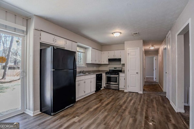 kitchen with a wealth of natural light, white cabinetry, under cabinet range hood, and black appliances