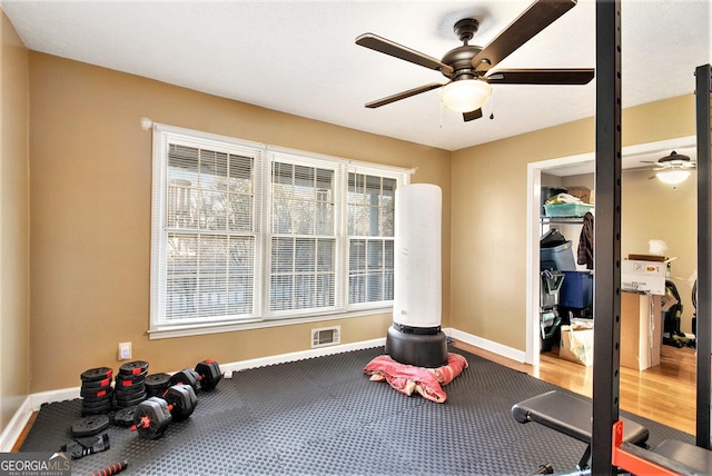 exercise room featuring a ceiling fan and baseboards