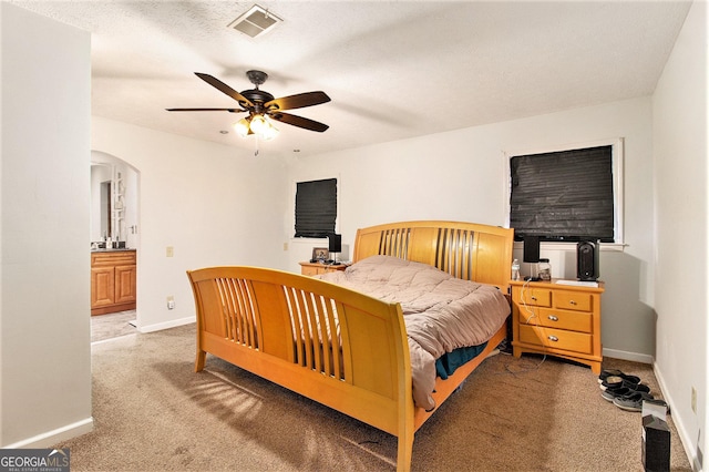 bedroom featuring arched walkways, light colored carpet, visible vents, and baseboards