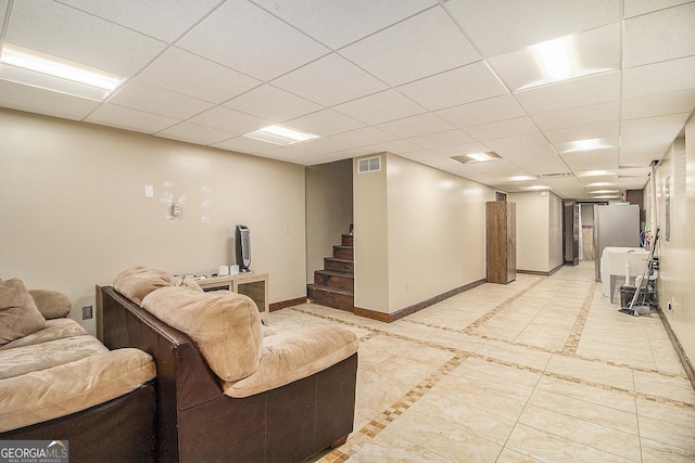 finished basement featuring stairs, a drop ceiling, visible vents, and baseboards