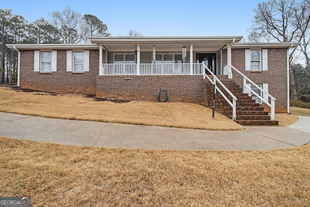 ranch-style home with covered porch, stairs, a front lawn, and brick siding