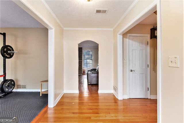 interior space featuring visible vents, arched walkways, light wood-style flooring, and a textured ceiling