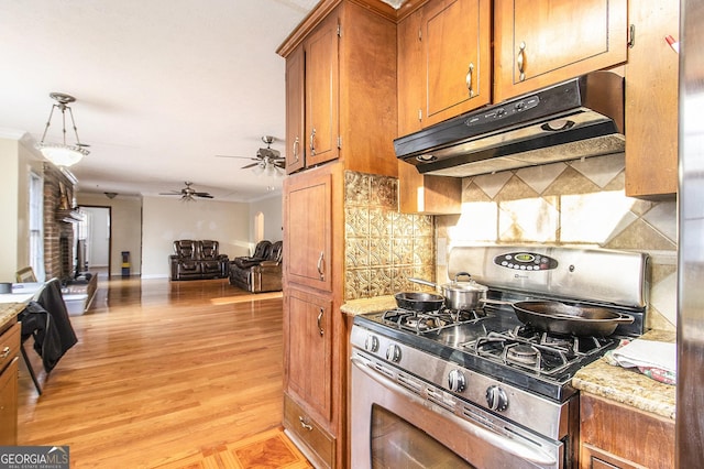 kitchen featuring light wood-style flooring, brown cabinetry, gas stove, open floor plan, and under cabinet range hood