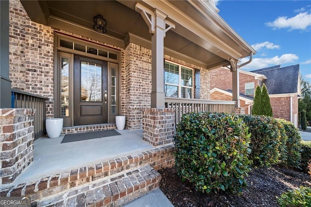 entrance to property with covered porch and brick siding