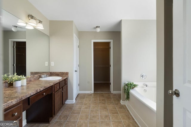 full bath featuring a garden tub, a spacious closet, vanity, baseboards, and tile patterned floors