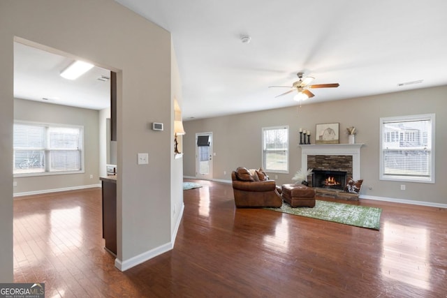 living room featuring dark wood-style floors, a healthy amount of sunlight, a fireplace, and baseboards