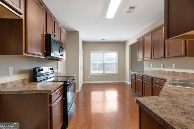 kitchen featuring baseboards, visible vents, electric stove, dark countertops, and wood finished floors