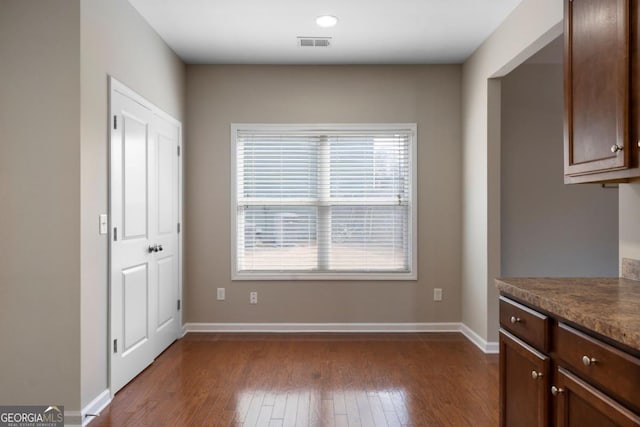 interior space with dark wood finished floors, visible vents, and baseboards