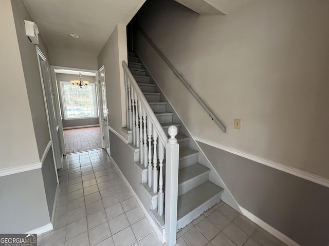 stairs featuring tile patterned flooring, baseboards, and an inviting chandelier