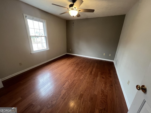 spare room featuring ceiling fan, baseboards, dark wood finished floors, and a textured ceiling