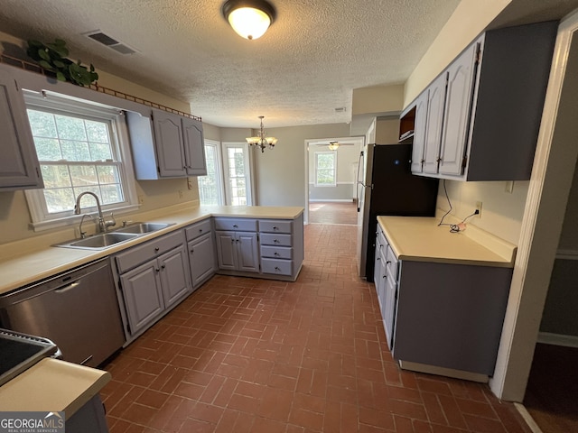 kitchen featuring gray cabinetry, a sink, light countertops, appliances with stainless steel finishes, and pendant lighting