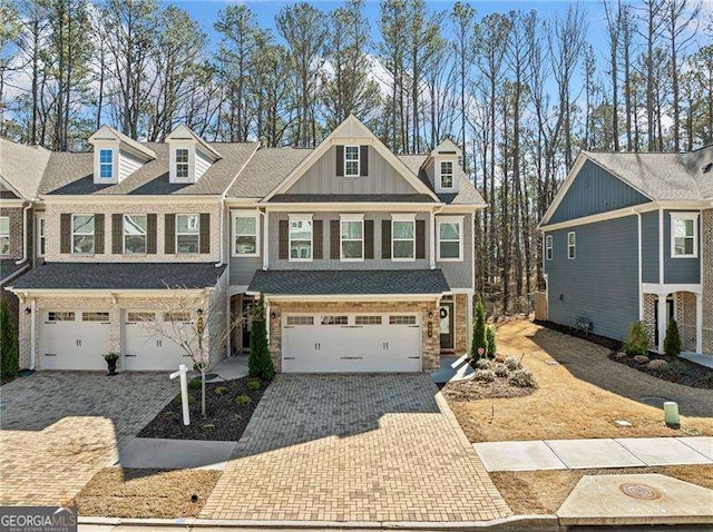 view of front facade with a garage, stone siding, decorative driveway, and board and batten siding