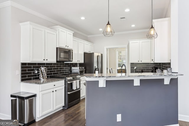 kitchen with visible vents, crown molding, a kitchen bar, a peninsula, and stainless steel appliances