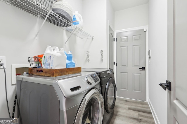 laundry area featuring light wood-type flooring, baseboards, separate washer and dryer, and laundry area