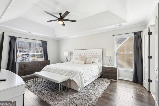 bedroom with dark wood finished floors, visible vents, and a tray ceiling