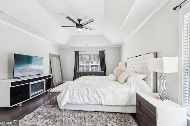 bedroom featuring ornamental molding, a ceiling fan, a tray ceiling, and wood finished floors