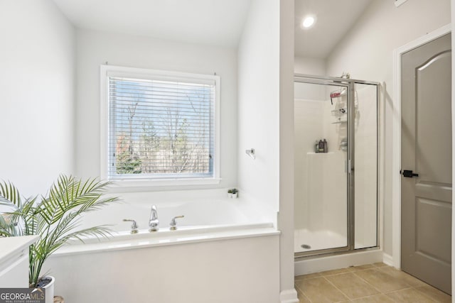 bathroom featuring tile patterned flooring, a bath, and a stall shower