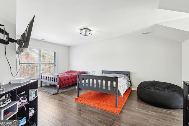 bedroom with wood finished floors, visible vents, and baseboards