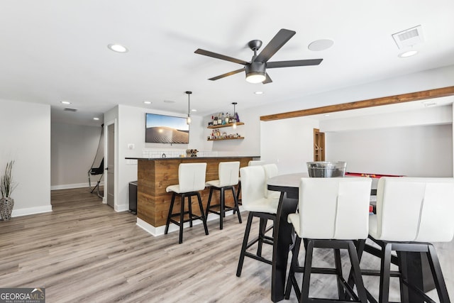 dining area with recessed lighting, visible vents, wet bar, and light wood-style floors