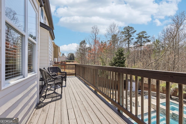 wooden deck featuring a patio area, a fenced in pool, and fence