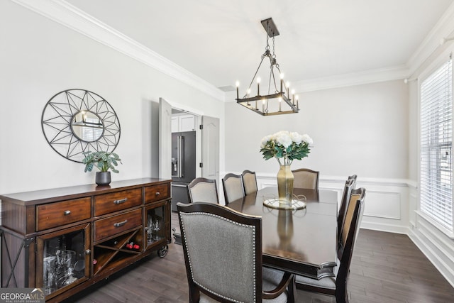 dining space with a decorative wall, ornamental molding, wainscoting, a notable chandelier, and dark wood-style flooring