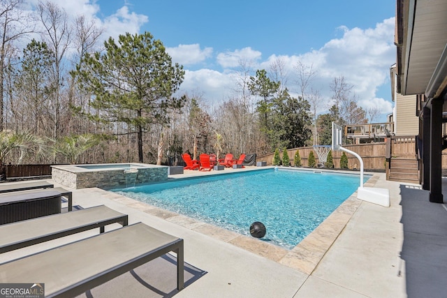 view of pool with a patio, fence, and a pool with connected hot tub