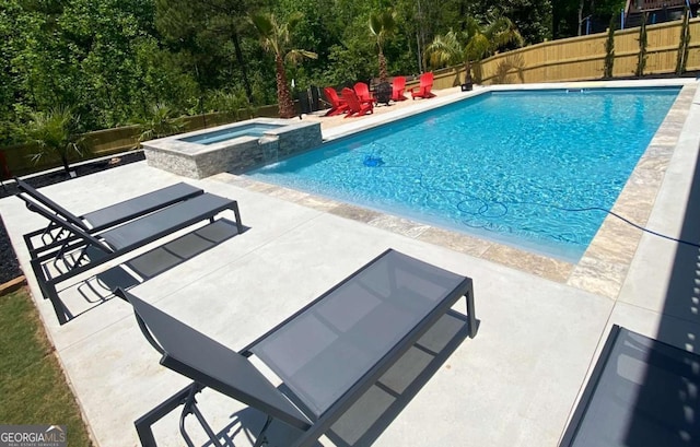 view of pool featuring a pool with connected hot tub, a patio area, and a fenced backyard