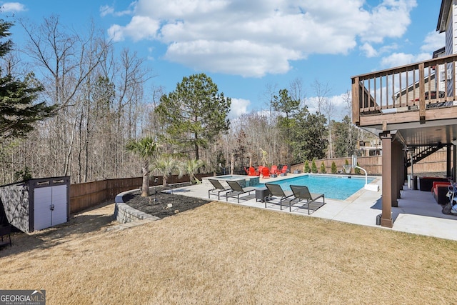 view of pool featuring a storage unit, a lawn, a patio, a fenced backyard, and an outdoor structure