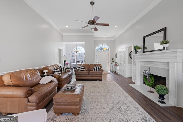 living room with ornamental molding, a high end fireplace, a ceiling fan, and wood finished floors