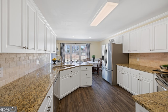 kitchen with white cabinets, appliances with stainless steel finishes, dark wood-type flooring, a peninsula, and a sink