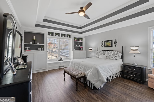 bedroom featuring ceiling fan, a tray ceiling, dark wood-type flooring, and ornamental molding